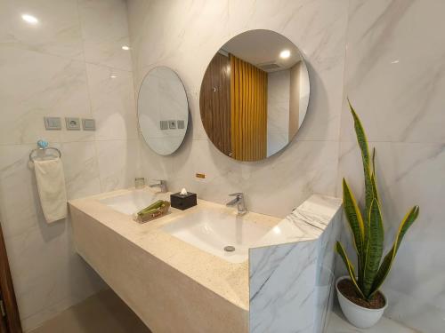 a bathroom with a sink and a mirror and a plant at Raja Hotel Kuta Mandalika Resort & Convention in Kuta Lombok