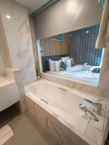 a bathroom with a bath tub with a large mirror at Raja Hotel Kuta Mandalika Resort & Convention in Kuta Lombok