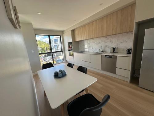 a kitchen with a white table and black chairs at 8 Ocean Rd in Auckland