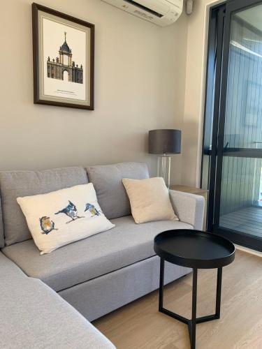 a living room with a gray couch and a table at 8 Ocean Rd in Auckland