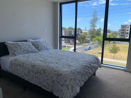 a bedroom with a bed and a large window at 8 Ocean Rd in Auckland