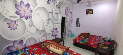 a bedroom with two beds and a wall with flowers at Kohli Niwas in Amritsar
