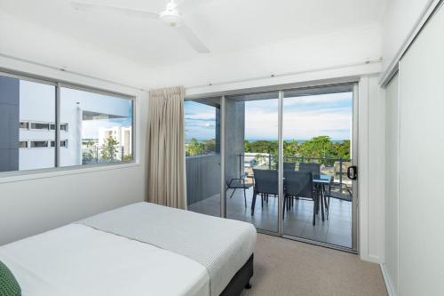 a bedroom with a bed and a balcony with a table at Panoramic views 3BR Cairns City Apartment in Cairns