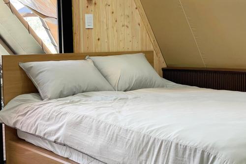 uma cama com lençóis brancos e almofadas em Pocheon Artemis Glamping em Pocheon