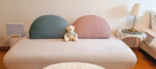 a stuffed teddy bear sitting on top of a bed at NK House in Anyang