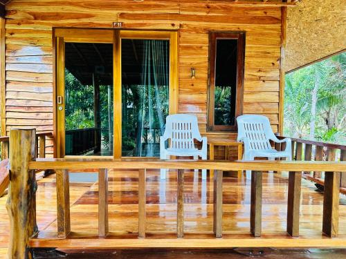 2 chaises sur la terrasse couverte d'une cabane en rondins dans l'établissement Koh Jum Bungalow & Hostel, à Ko Jum