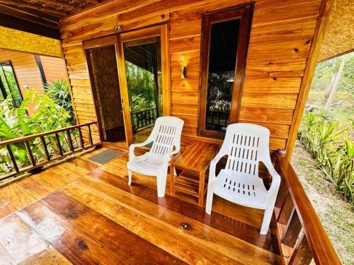 dos sillas blancas sentadas en el porche de una cabaña en Koh Jum Bungalow & Hostel, en Ko Jum
