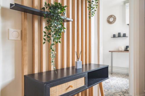 une commode noire avec une plante sur un mur dans l'établissement MM Suites Centre Bacquenois, à Reims