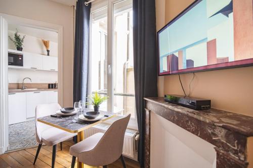 une petite salle à manger avec une table et une télévision dans l'établissement MM Suites Centre Bacquenois, à Reims