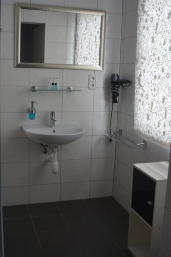 a white bathroom with a sink and a mirror at Budgethotel Stadtbett Wolfsburg in Wolfsburg