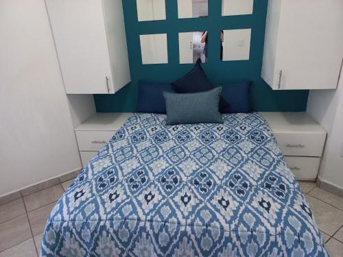 a bedroom with a bed with a blue and white comforter at SUNSET BEACH in Uvongo Beach