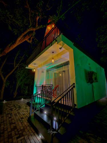 a green house with a balcony at night at Residence Inn in Udawalawe