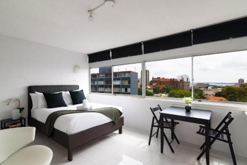 Schlafzimmer mit einem Bett, einem Tisch und einem Fenster in der Unterkunft Studio with Stunning Views and Free Parking in Sydney
