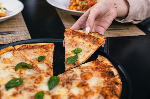 a person holding a slice of pizza in a pan at The Abdali Boulevard Hotel in Amman