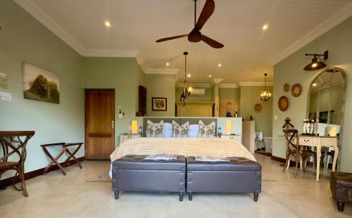 a bedroom with a large bed with a ceiling fan at Kambaku River Lodge in Malelane