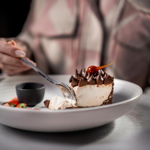 a piece of cake on a plate with a fork at The Abdali Boulevard Hotel in Amman