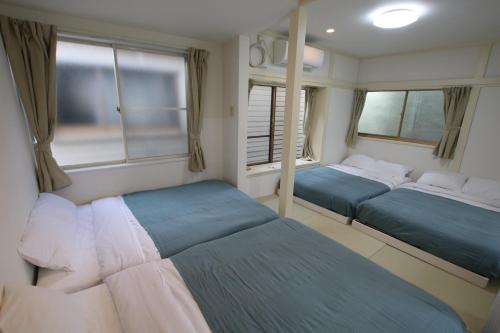 a bedroom with two beds and two windows at 大山町戸建 in Tokyo