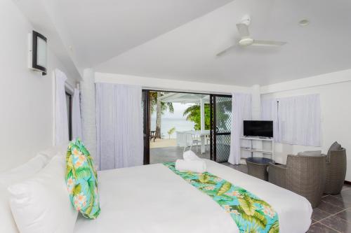 a white bedroom with a bed and a living room at Bella Beach Bungalows in Rarotonga