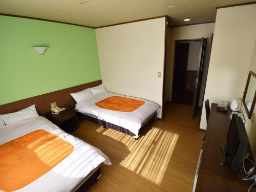 two beds in a room with green walls at おやど 心 in Takayama