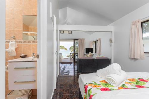 a bedroom with a bed and a bathroom with a sink at Bella Beach Bungalows in Rarotonga
