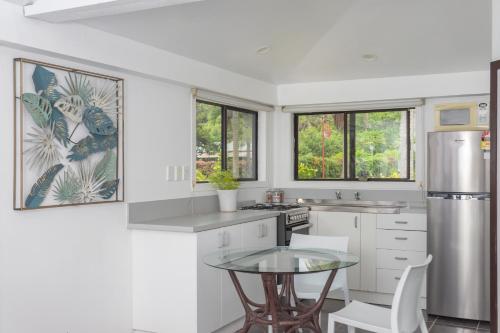 a kitchen with white cabinets and a glass table at Bella Beach Bungalows in Rarotonga