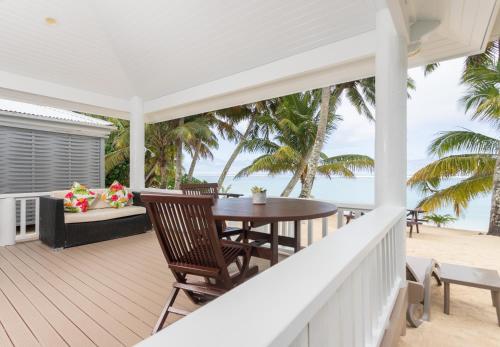 a porch with a table and chairs on the beach at Bella Beach Bungalows in Rarotonga