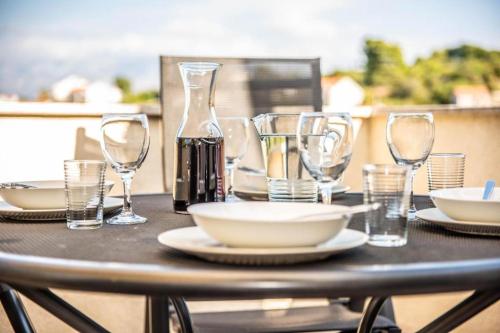 a table with glasses and plates and a bottle at Apartments Marijin Dvor in Splitska