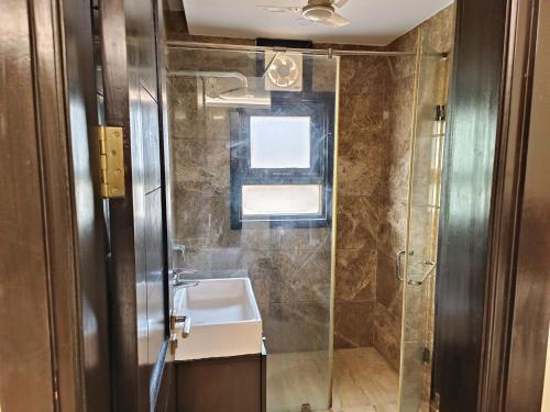 La salle de bains est pourvue d'un lavabo et d'une douche. dans l'établissement Greenleaf Apartment and Suites, Greater Kailash 1, à New Delhi