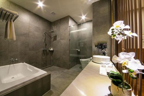 a bathroom with a tub and a shower and a sink at Epoche Hotel in Jinju