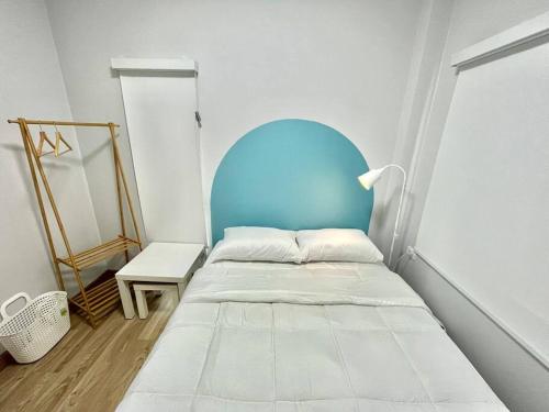 ein kleines Schlafzimmer mit einem Bett mit blauem Kopfteil in der Unterkunft Borbaimai home in Chiang Rai