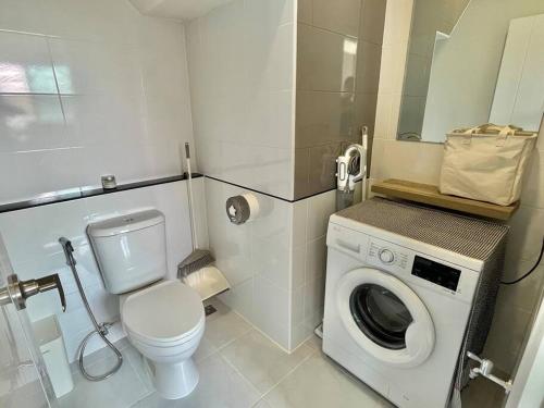 a bathroom with a toilet and a washing machine at Borbaimai home in Chiang Rai