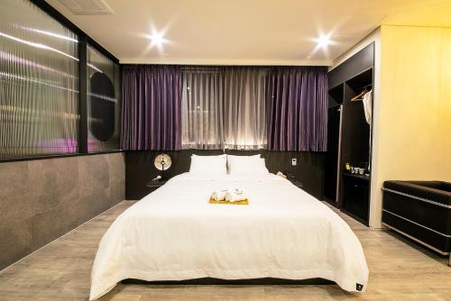 a large white bed in a room with purple curtains at Epoche Hotel in Jinju