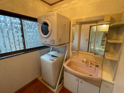 a small bathroom with a washing machine and a sink at YAKUSHIMA YUDOMARI443 in Yudomari