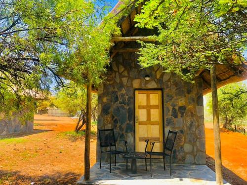 a stone house with chairs and a table in front of it at Big Valley Game Lodge in Lobatse