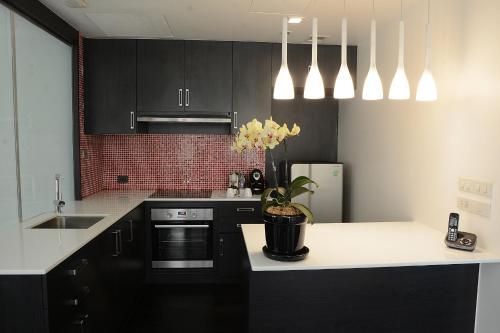 a kitchen with black cabinets and a white counter top at Novotel Bangkok IMPACT in Nonthaburi