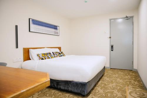 a bedroom with a white bed and a wooden table at The Concept Hotel KL- TBS in Kuala Lumpur