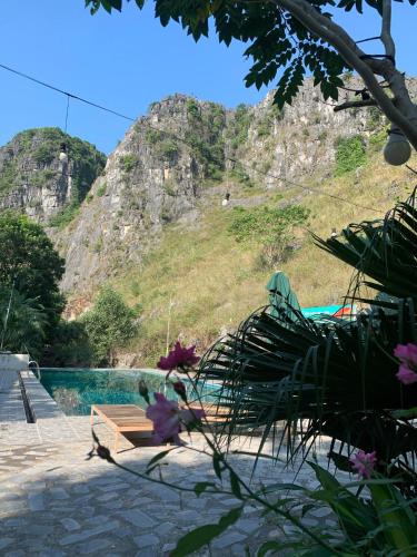 a bench next to a swimming pool with a mountain at Hang Lan Bungalow in Ninh Binh