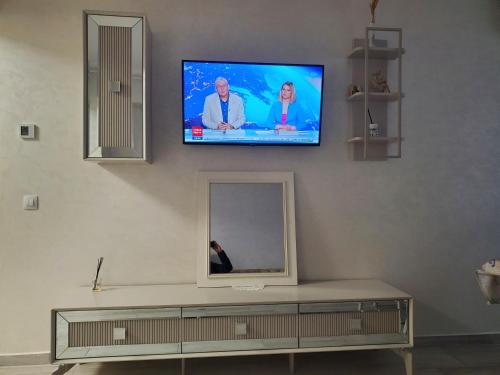 a flat screen tv on a wall with a mirror at Luxury Apartament Bacovia in Bacău