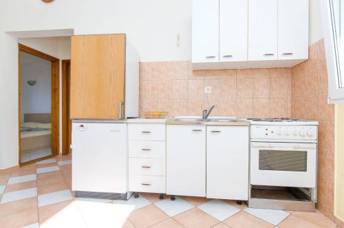 eine Küche mit weißen Schränken und einer Spüle in der Unterkunft Apartments Sandra in Stomorska