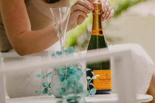 a woman holding a champagne bottle and a glass at Bamboo Villa - Pet friendly luxury Villa next to Botanical Gardens in Edge Hill