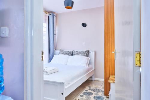 een wit bed in een kamer met een raam bij A beautiful one bedroom with a rooftop pool in Kiambu