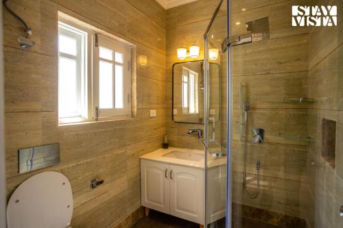uma casa de banho com um lavatório, um chuveiro e um espelho. em StayVista at Midsummer Moon em Srinagar