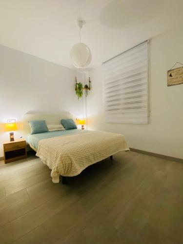 a white bedroom with a bed and a lamp at EL MARINERITO Alcocebre in Alcossebre