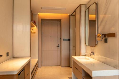 a bathroom with two sinks and a mirror and a door at Guus Hotel in Zengcheng