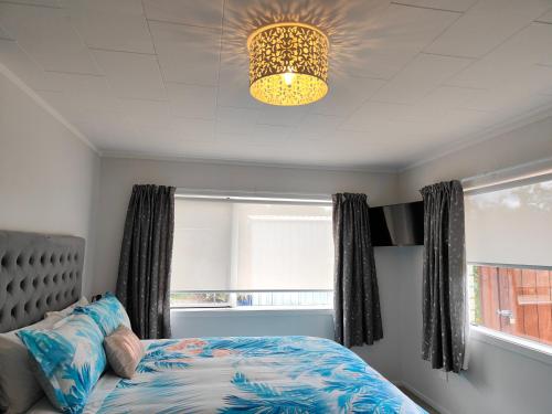 a bedroom with a bed and a chandelier at Kerikeri Sunny Modern 2 Bedroom Apartment in Kerikeri