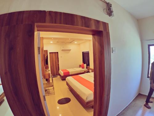 a bedroom with two beds and a mirror at Hotel Nawanagar Residency in Jamnagar