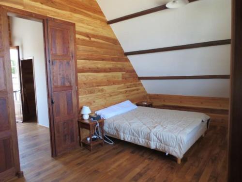 Un dormitorio con una cama y una pared de madera. en Villa Joséphine sur la plage, en Saint-Paul
