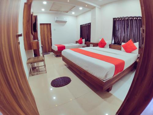 a bedroom with two beds with red pillows at Hotel Nawanagar Residency in Jamnagar