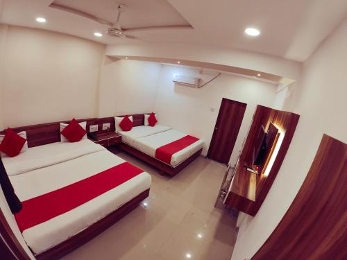 a room with two beds and a television in it at Hotel Nawanagar Residency in Jamnagar