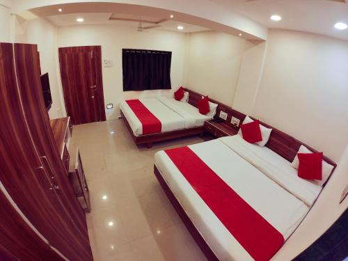a bedroom with two beds and a tv in it at Hotel Nawanagar Residency in Jamnagar